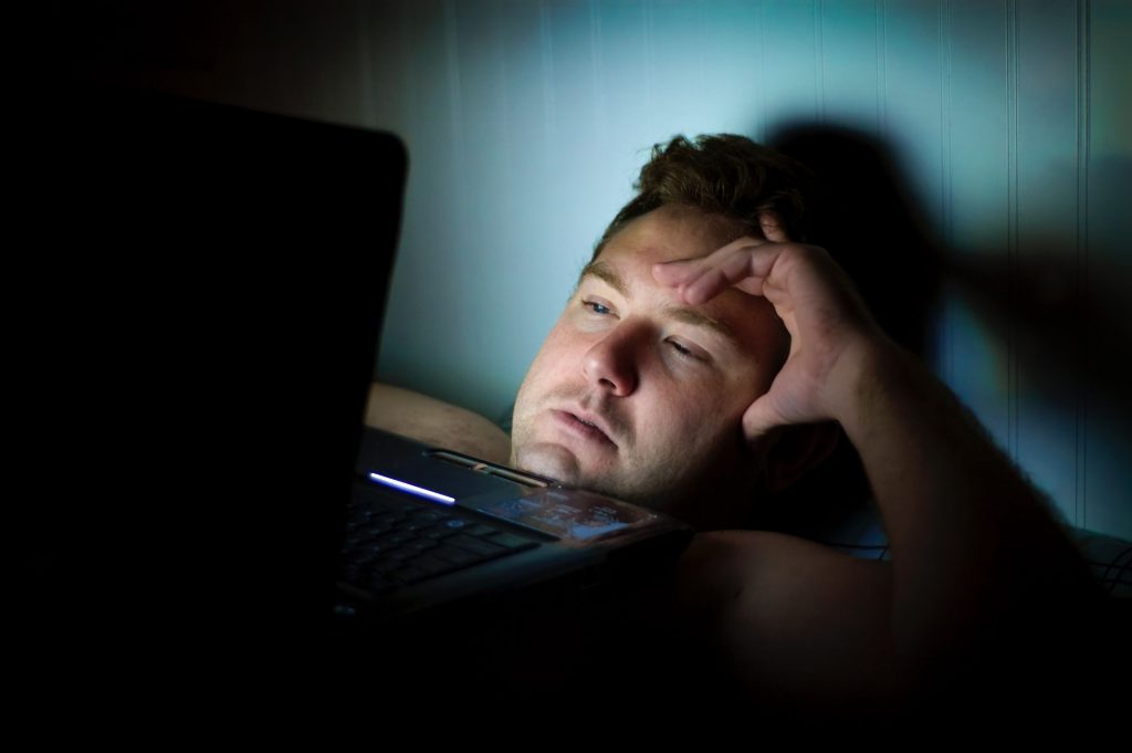 Man lay in bed with laptop